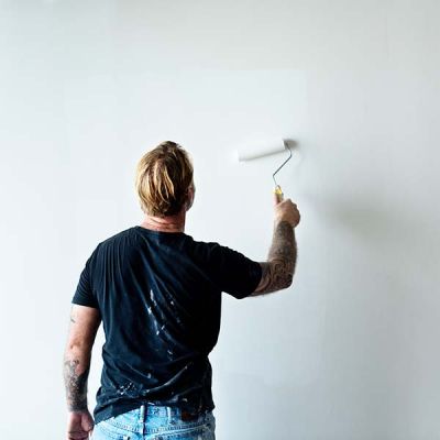 man painting interior wall of home