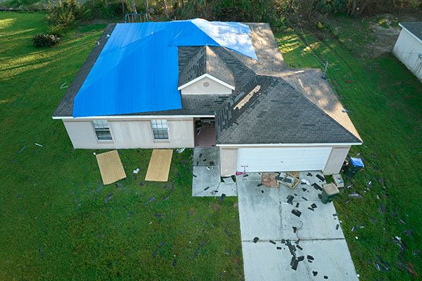 home with tarp covering roof damages
