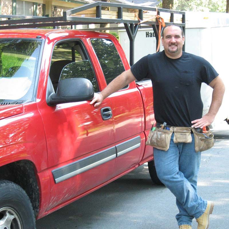owner leaning against work truck with tools on hip